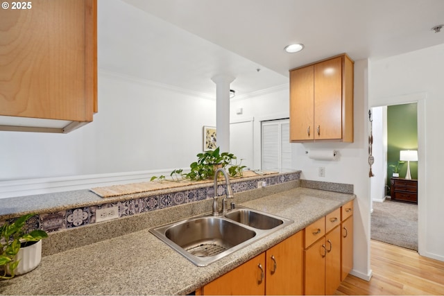 kitchen featuring light wood-type flooring, ornamental molding, sink, and ornate columns