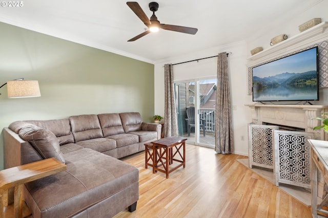 living room with ornamental molding, ceiling fan, and light wood-type flooring