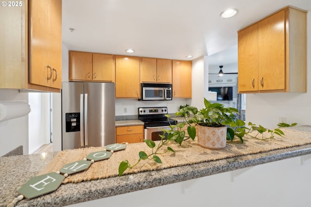 kitchen featuring ceiling fan, stainless steel appliances, kitchen peninsula, and light stone countertops