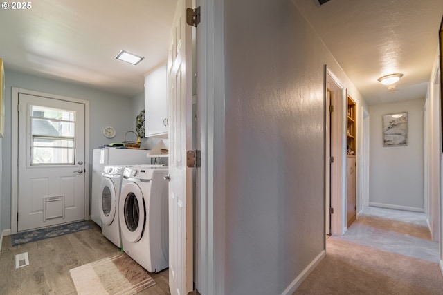 washroom featuring washing machine and dryer, light carpet, and cabinets