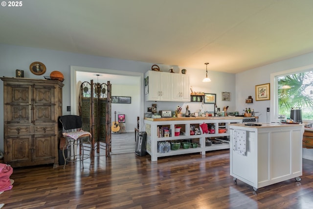 kitchen with a center island, white cabinets, dark wood-type flooring, and decorative light fixtures