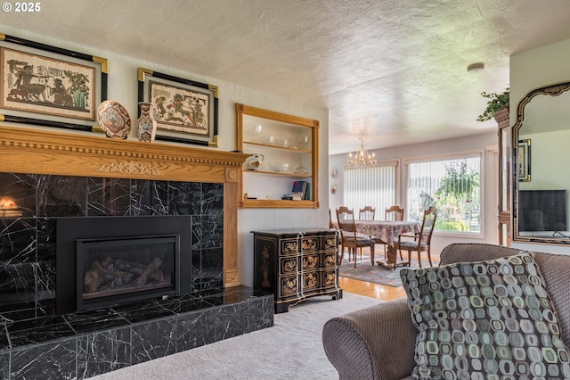 carpeted living room featuring built in shelves, a high end fireplace, a textured ceiling, and an inviting chandelier