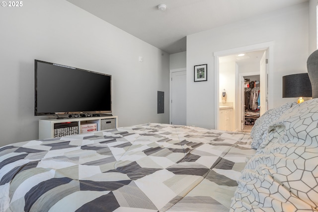 bedroom featuring ensuite bath, a walk in closet, a closet, and electric panel