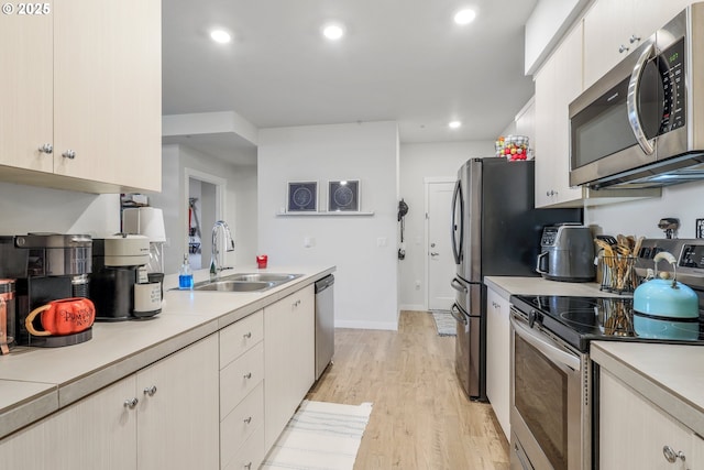 kitchen featuring appliances with stainless steel finishes, sink, and light hardwood / wood-style flooring