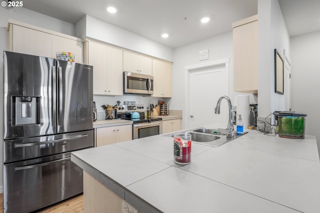 kitchen with tile counters, cream cabinetry, appliances with stainless steel finishes, and sink