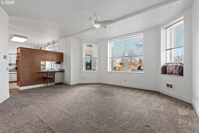 unfurnished living room with ceiling fan, carpet flooring, and a textured ceiling