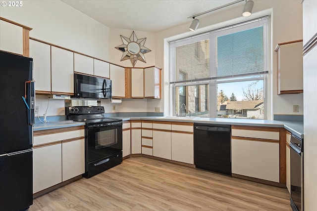 kitchen with a sink, black appliances, light countertops, and white cabinets