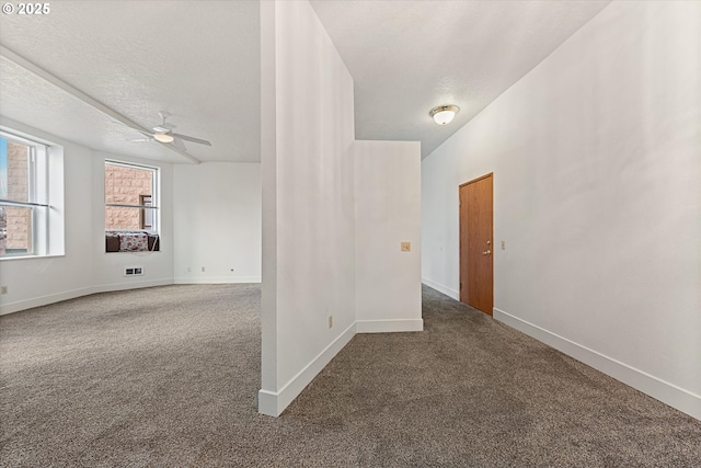 empty room with carpet, a textured ceiling, and baseboards