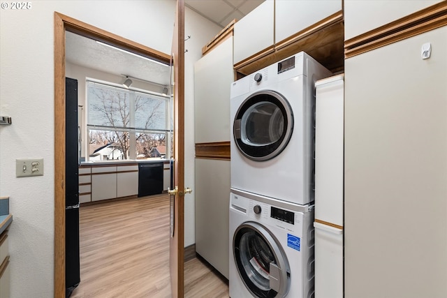 clothes washing area with stacked washer / drying machine, sink, and light wood-type flooring