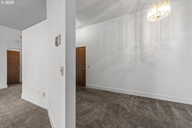 interior space featuring an inviting chandelier, dark carpet, and a textured ceiling