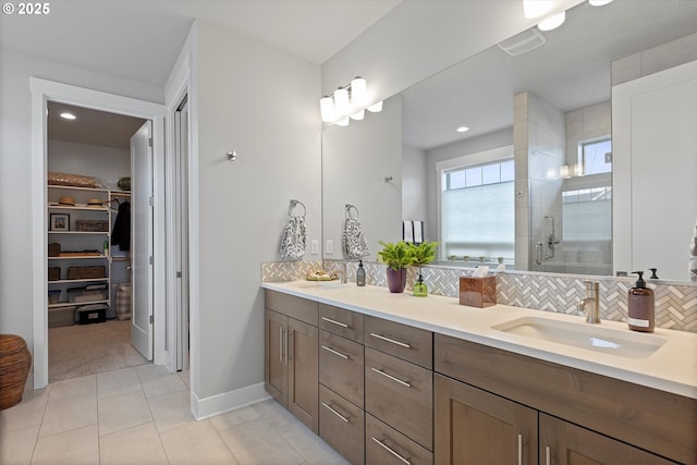 full bathroom with a stall shower, a sink, backsplash, and tile patterned floors