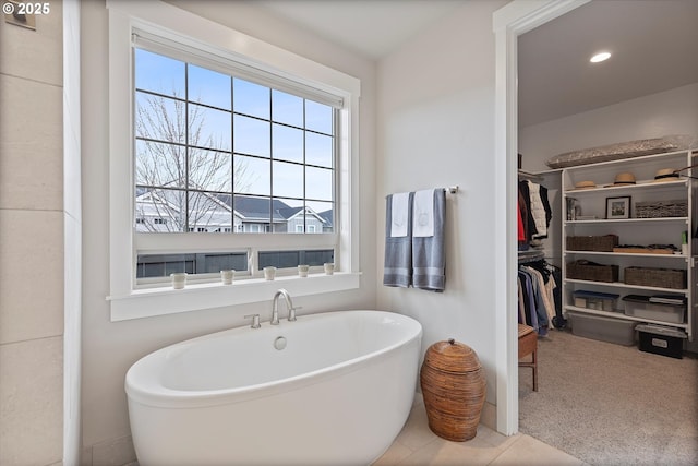 bathroom with a soaking tub, a walk in closet, and recessed lighting