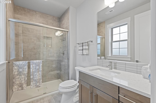 full bathroom with tasteful backsplash, visible vents, toilet, a stall shower, and vanity