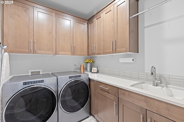 clothes washing area featuring separate washer and dryer, a sink, and cabinet space