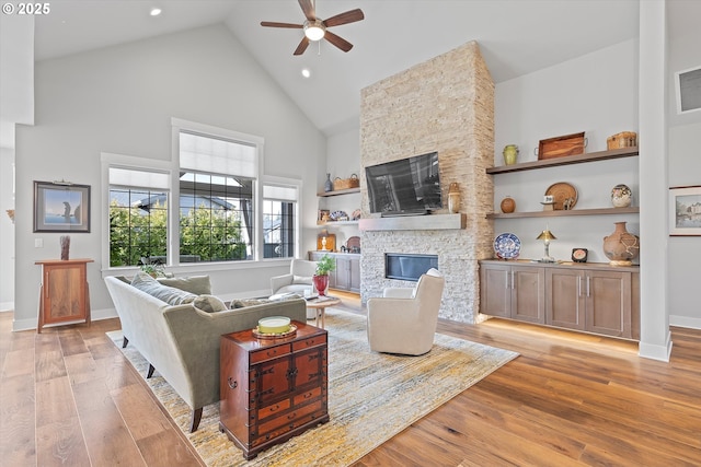 living room with a fireplace, light wood-style floors, ceiling fan, high vaulted ceiling, and baseboards