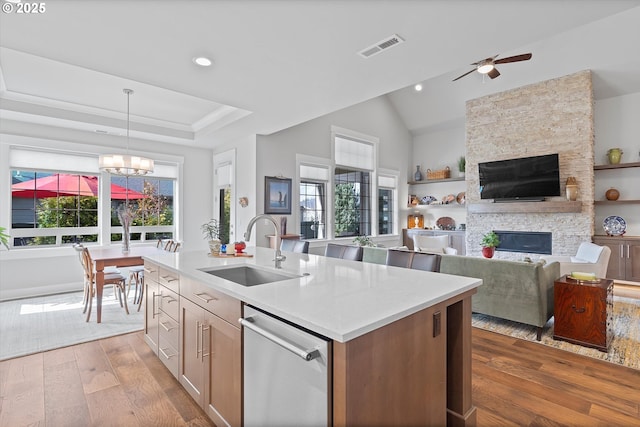 kitchen with a wealth of natural light, visible vents, stainless steel dishwasher, a sink, and a stone fireplace