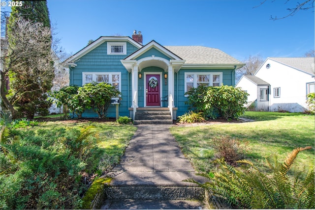 bungalow-style house featuring roof with shingles, a chimney, and a front yard