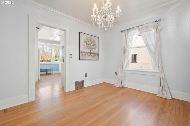 spare room featuring light wood-style floors, visible vents, ornamental molding, and baseboards