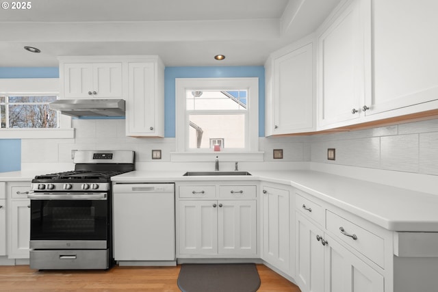 kitchen with white cabinets, stainless steel gas stove, a sink, dishwasher, and under cabinet range hood