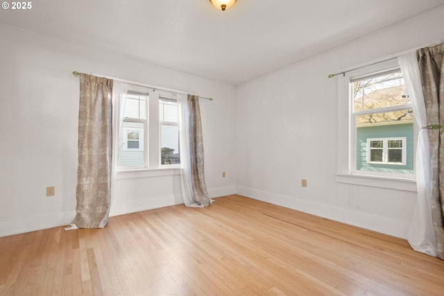 empty room with baseboards, light wood-style flooring, and a healthy amount of sunlight