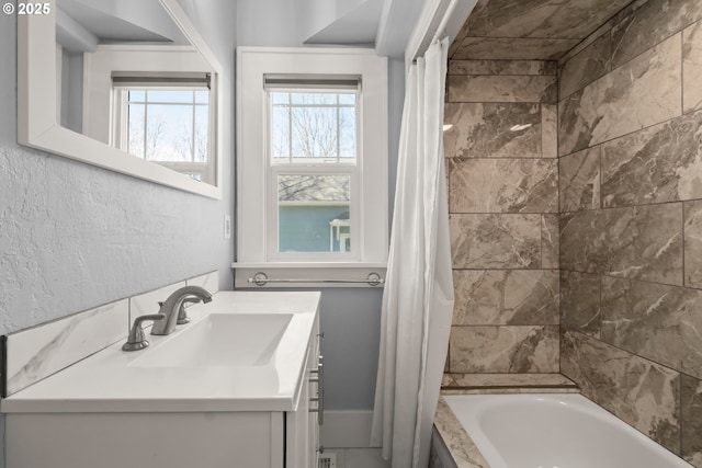 bathroom featuring a textured wall, vanity, and shower / bathtub combination with curtain