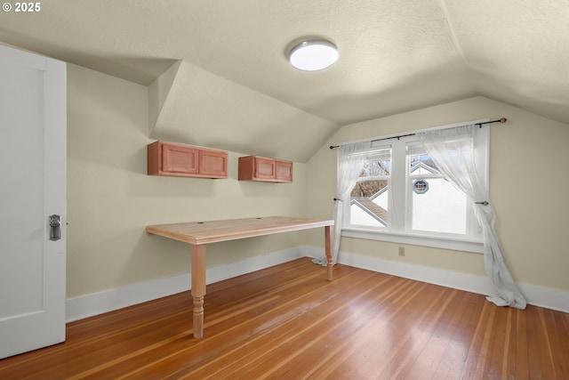 bonus room with a textured ceiling, light wood finished floors, lofted ceiling, and baseboards