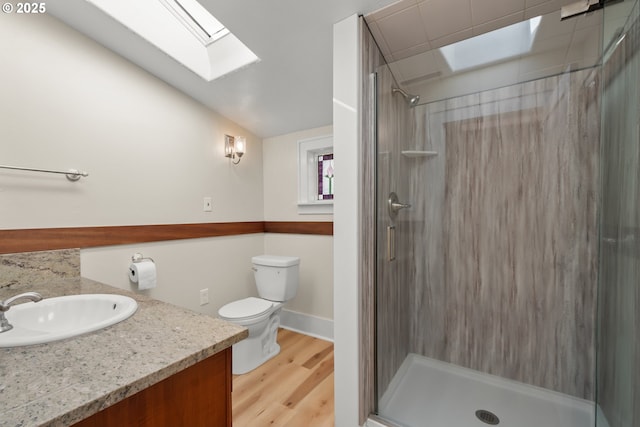 bathroom with toilet, a stall shower, vaulted ceiling with skylight, and wood finished floors