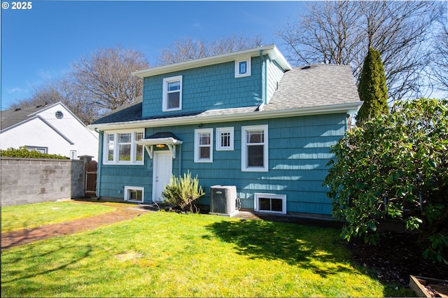 back of house with roof with shingles, fence, central AC, and a yard