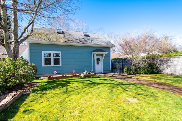 view of front facade with a shingled roof, a front yard, and fence