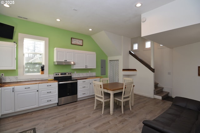 kitchen with butcher block counters, stainless steel range with electric cooktop, light wood-style flooring, and white cabinets