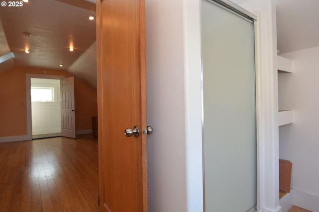 interior space with hardwood / wood-style flooring, baseboards, and vaulted ceiling