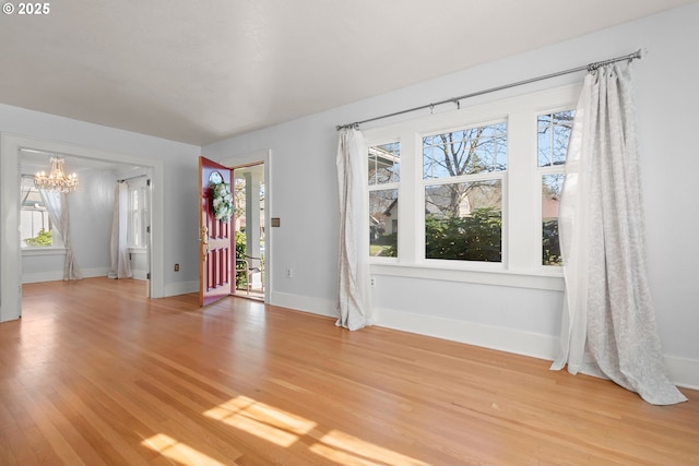 interior space with a healthy amount of sunlight, light wood-style flooring, a chandelier, and baseboards