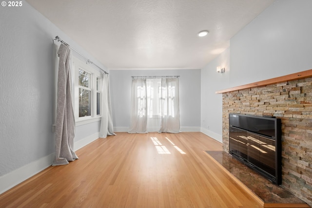 unfurnished living room featuring light wood-type flooring, a fireplace, and baseboards