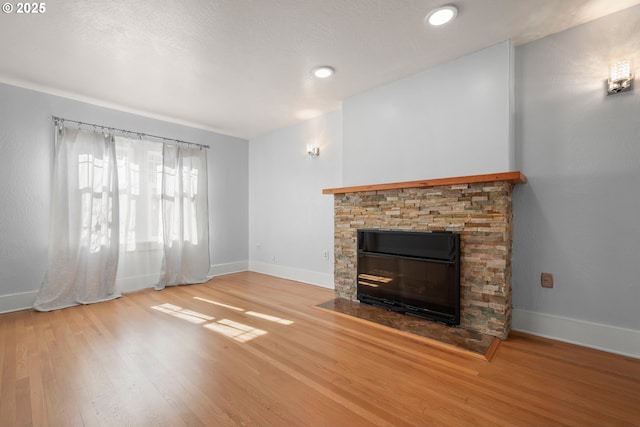 unfurnished living room featuring a fireplace, baseboards, and wood finished floors