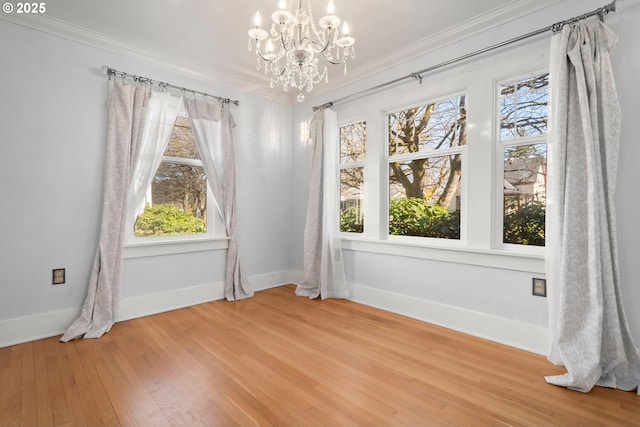 unfurnished dining area featuring a notable chandelier, wood-type flooring, baseboards, and crown molding