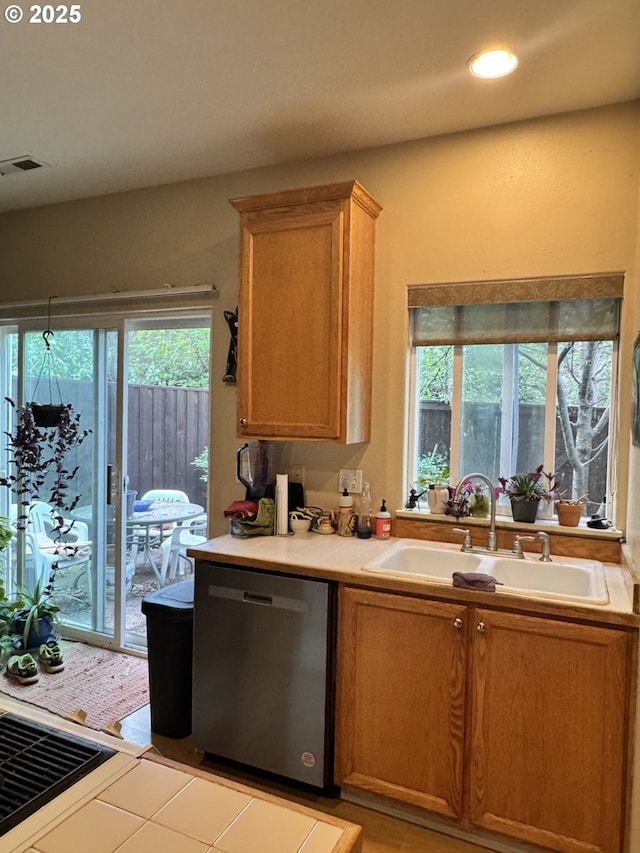 kitchen featuring dishwasher, a sink, recessed lighting, and tile countertops
