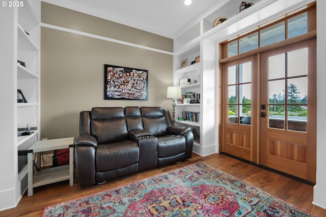 living room with dark wood-type flooring, built in features, ornamental molding, and french doors