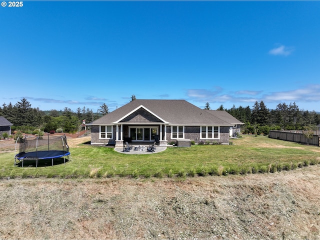 rear view of property featuring a yard, a patio, and a trampoline