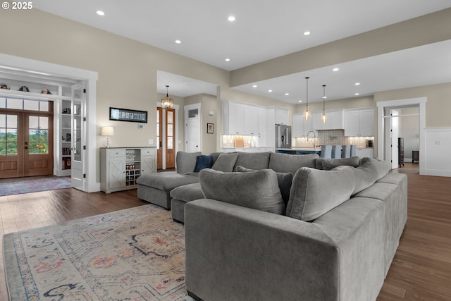 living room with an inviting chandelier, sink, dark wood-type flooring, and built in features