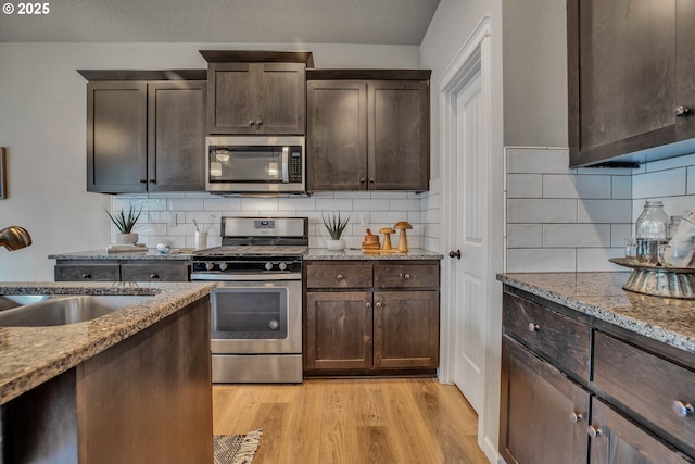 kitchen with tasteful backsplash, light hardwood / wood-style flooring, stainless steel appliances, and dark brown cabinets