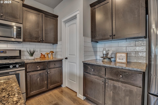 kitchen with dark brown cabinetry, light stone countertops, and stainless steel appliances