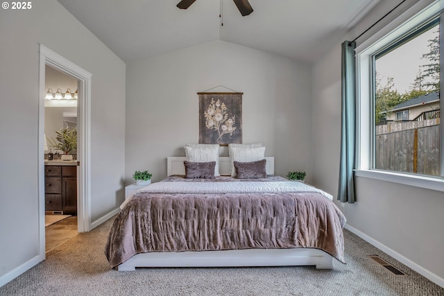 bedroom with carpet, ensuite bathroom, vaulted ceiling, and ceiling fan