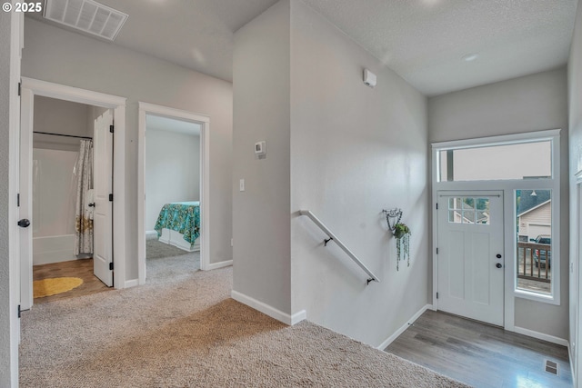 entryway with light carpet and a textured ceiling