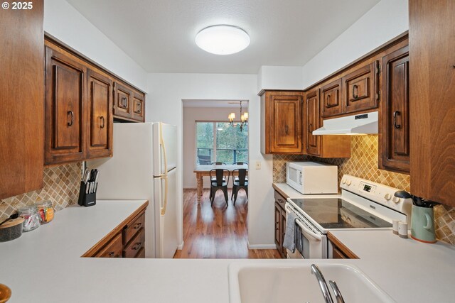 18308 NE Cole Witter Rd, Battle Ground, WA 98604 - kitchen with under cabinet range hood, white appliances, a sink, a chandelier, and light countertops