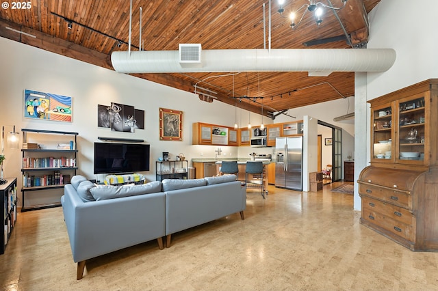 living area featuring visible vents, wooden ceiling, track lighting, and a high ceiling