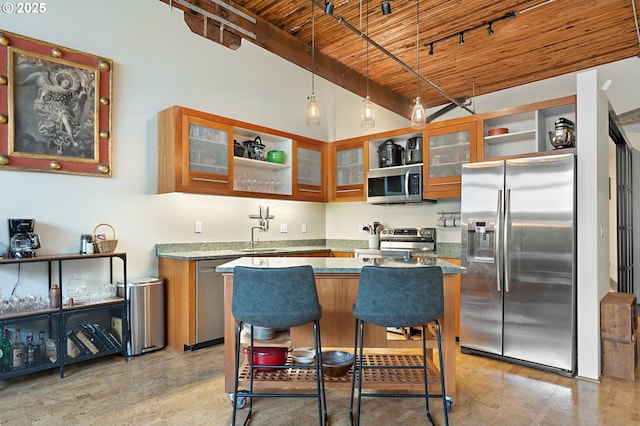 kitchen featuring a center island, beam ceiling, wooden ceiling, brown cabinetry, and stainless steel appliances