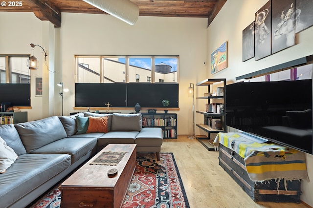 living room featuring light wood-type flooring, beam ceiling, wood ceiling, and a towering ceiling