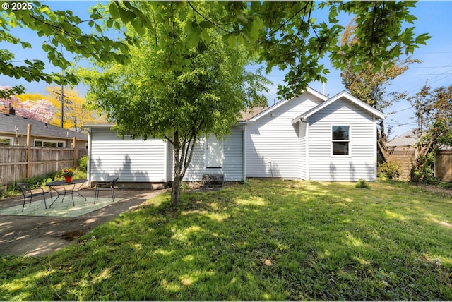 back of house featuring fence, a lawn, and a patio area