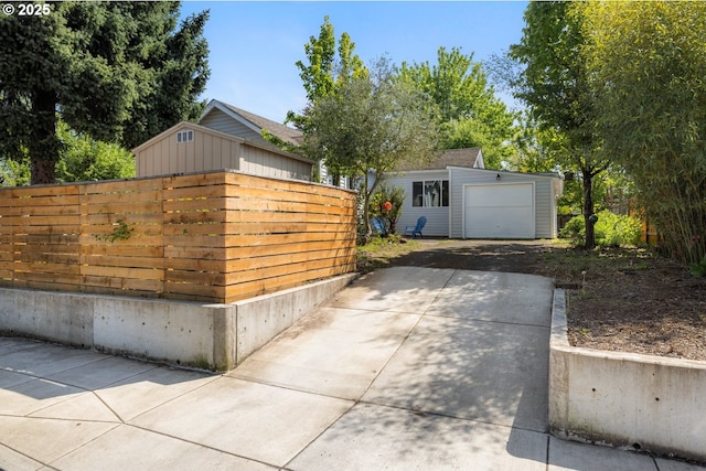 detached garage featuring driveway and fence