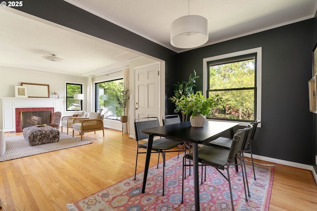 6833 NE 18th Ave, Portland, OR 97211 - dining room featuring plenty of natural light, light wood-type flooring, a tile fireplace, ornamental molding, and baseboards